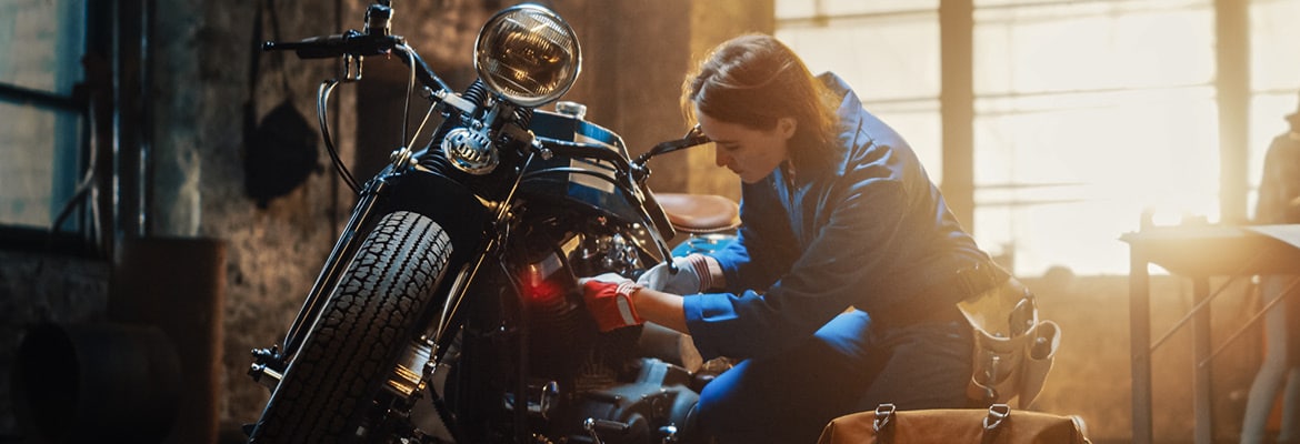 A person in a garage doing maintenance on a motorcycle