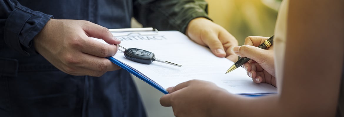 Buying a car at a dealership and signing contract during key handoff.