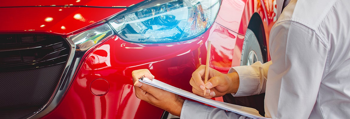 Picture of a person holding a clipboard inspecting a red car