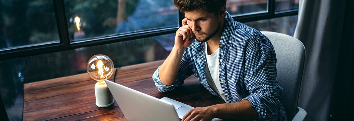 Man sitting at a desk looking at a laptop computer