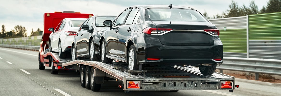 Three cars being towed on an open transport trailer