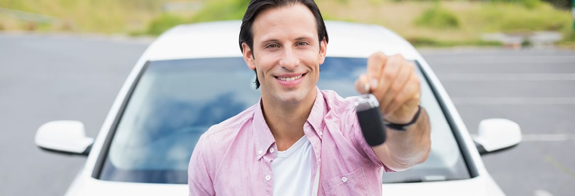 Man holding up car keys in front of his new car