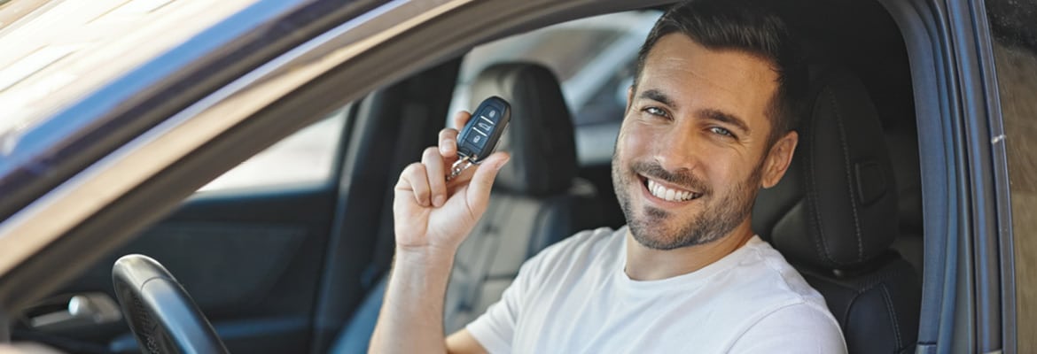 A man sitting in the driver's seat of a car, holding a set of car keys