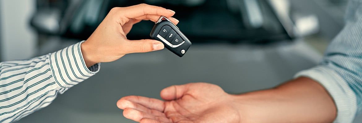 Close up of two people's hands. One hand is placing car keys in the other hand.