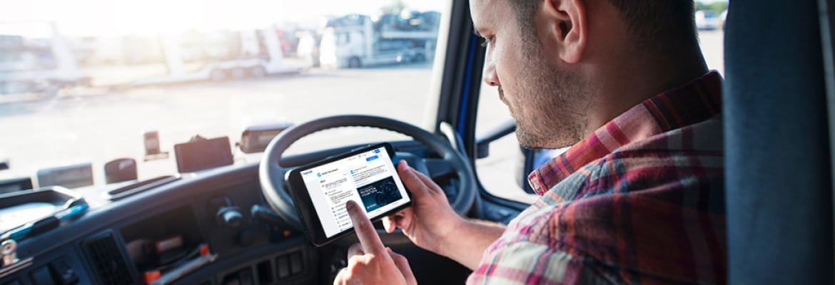 Truck driver behind the wheel looking at a handheld tablet