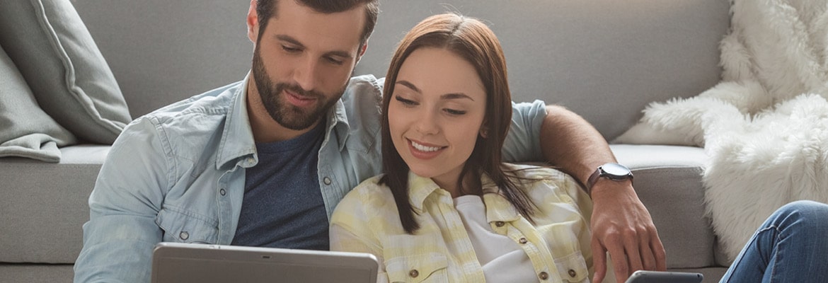 A couple sitting on a couch looking at a laptop computer