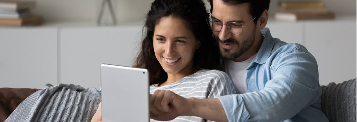 A man and a woman smiling looking at a tablet