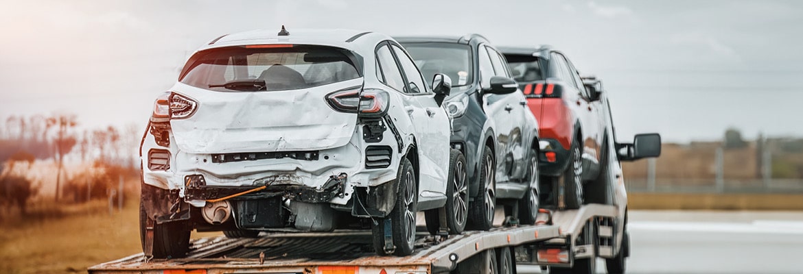 Picture of several damaged cars loaded on to an auto transport truck.