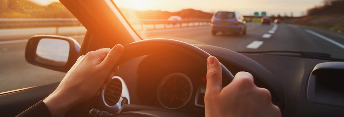 Person driving on the highway, hands on the steering wheel.