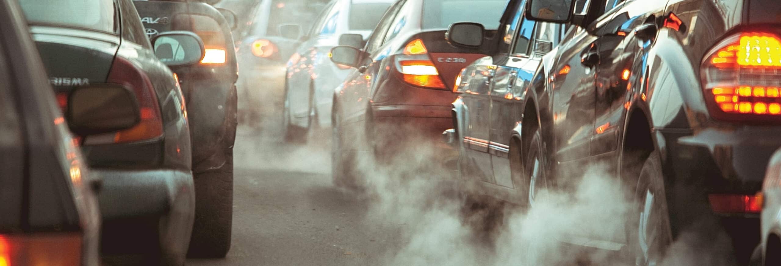 Cars with break lights on among clouds of exhaust