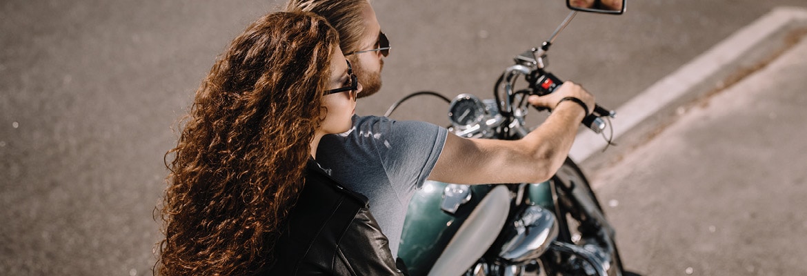 Two people on a motorcycle on a road.