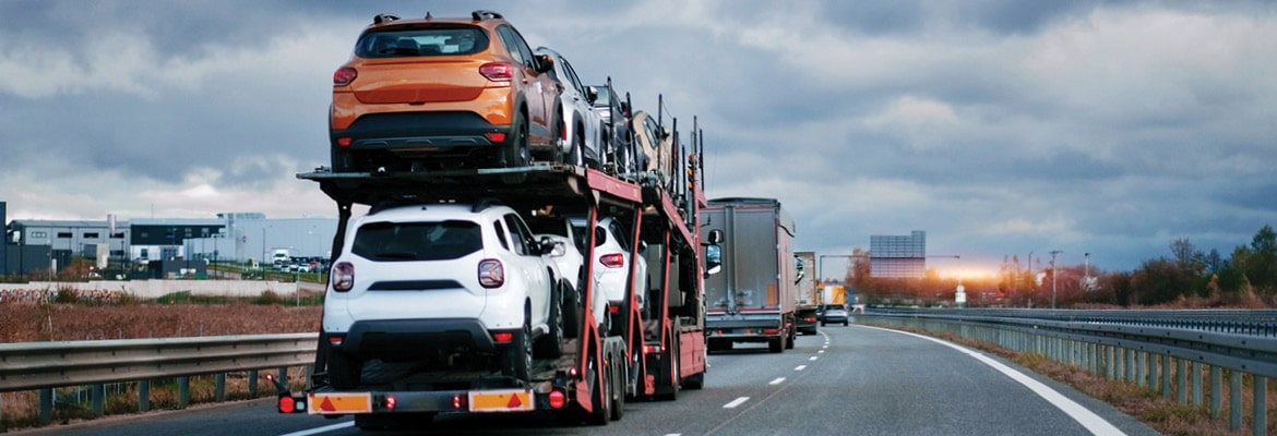 An open transport truck hauling cars on a highway