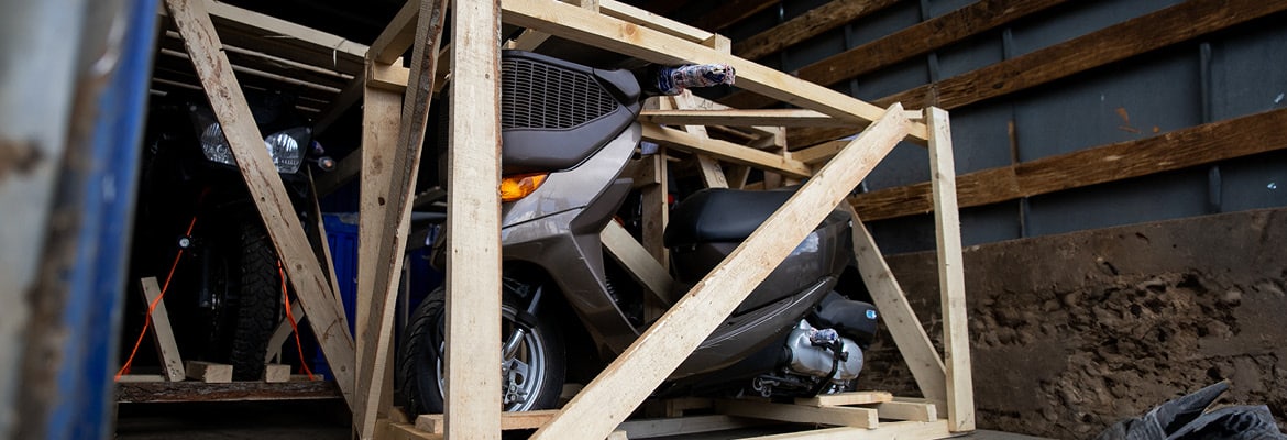 A motorcycle and motor scooter being loaded into a transport truck