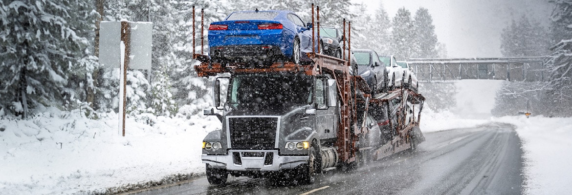 Truck hauling vehicles on a snowy day.