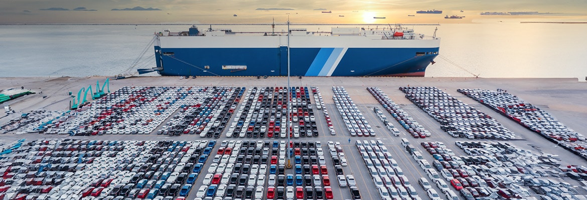 Large roll on/roll off ship with a parking lot of vehicles waiting to be loaded