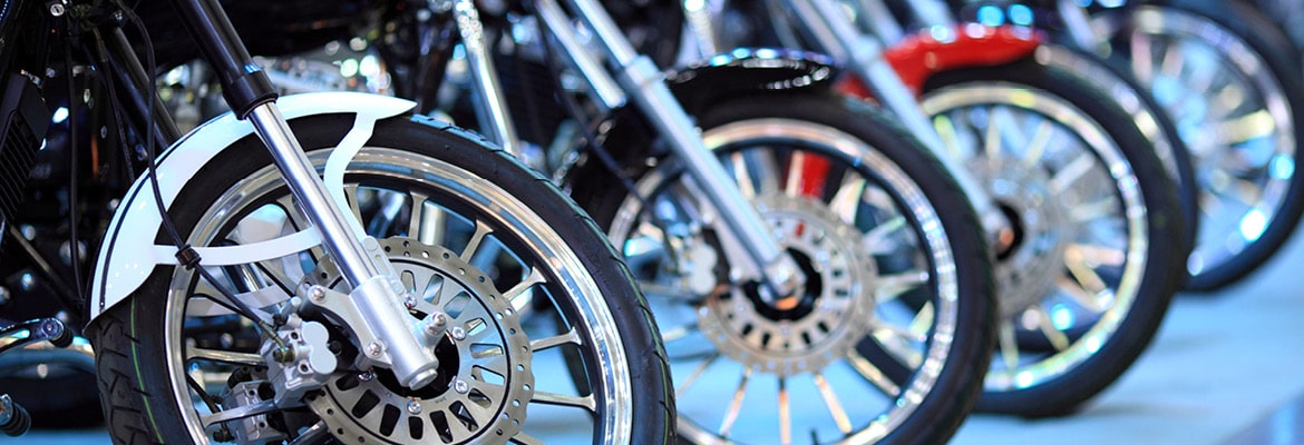 New motorcycles lined up with a close up on the front wheels