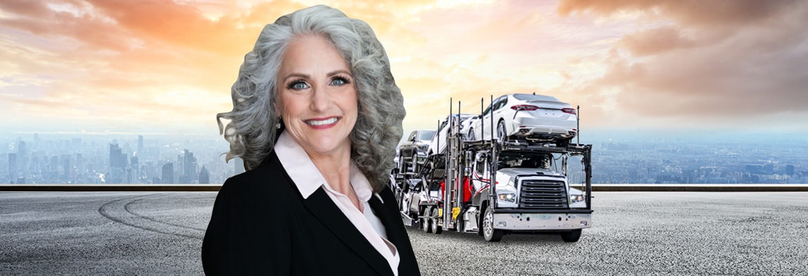 Dina Gifford's image in front of an open car carrier loaded with new vehicles.