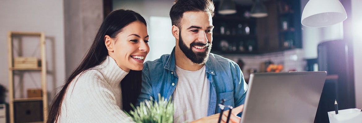 Two people smiling and looking at a laptop screen