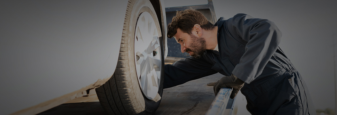 A man loading vehicle onto a car carrier for auto transport.