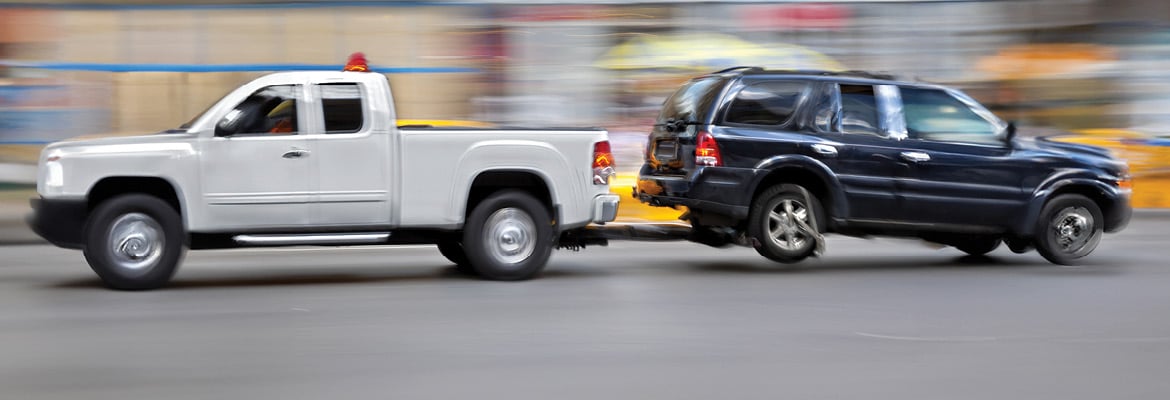 Vehicle being repossessed transported by a trailer hitch.