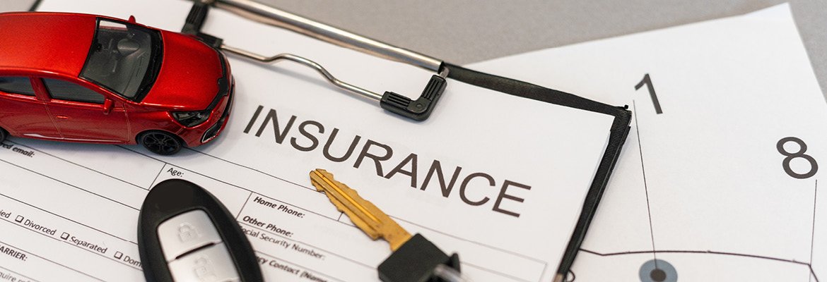 Car keys and red toy car on auto insurance claim form