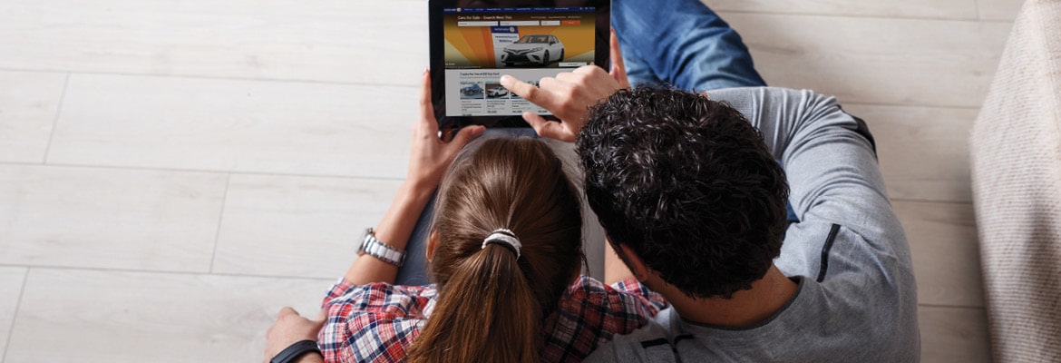 Man and women selling used car on AutoTrader website on laptop.