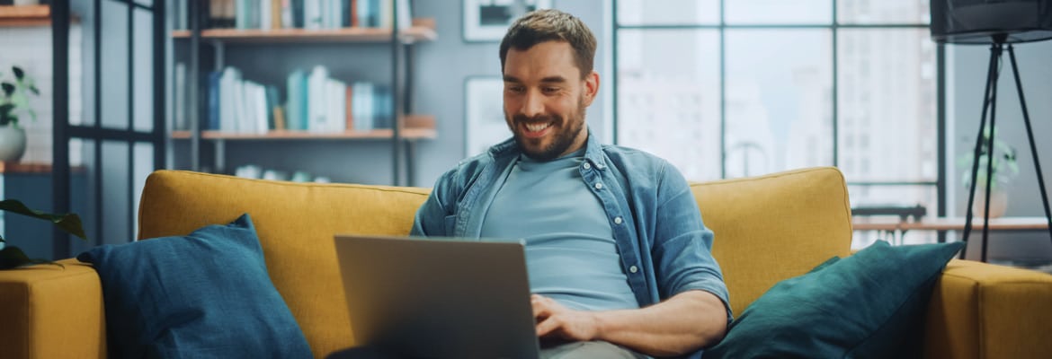 Man on couch using laptop to sell his car on Carvana.