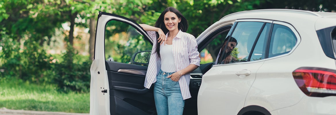 Woman standing next to car with driver door open.