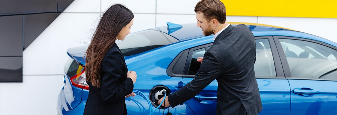 Car salesman demonstrating EV charging to car buyer.