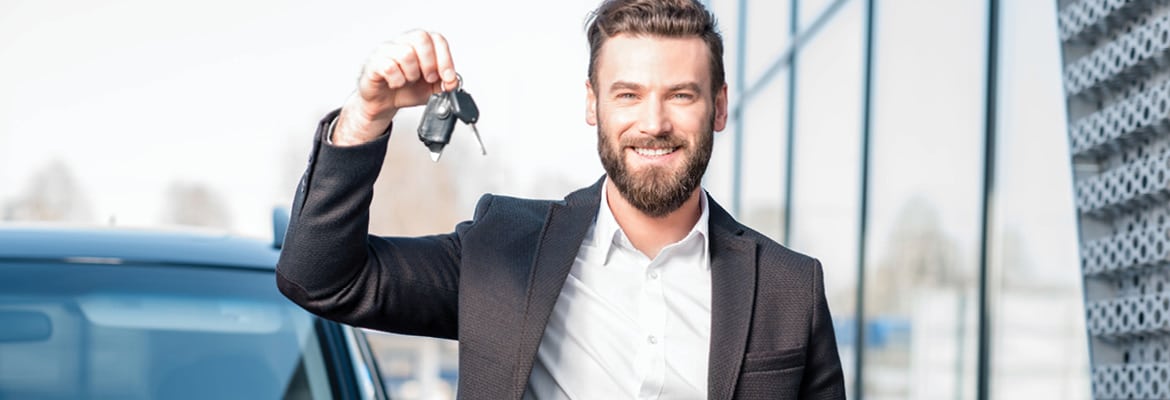 A man in a suit holding keys to car bought on TrueCar.