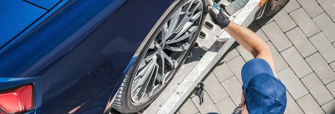 Professional securing car on open transport trailer.