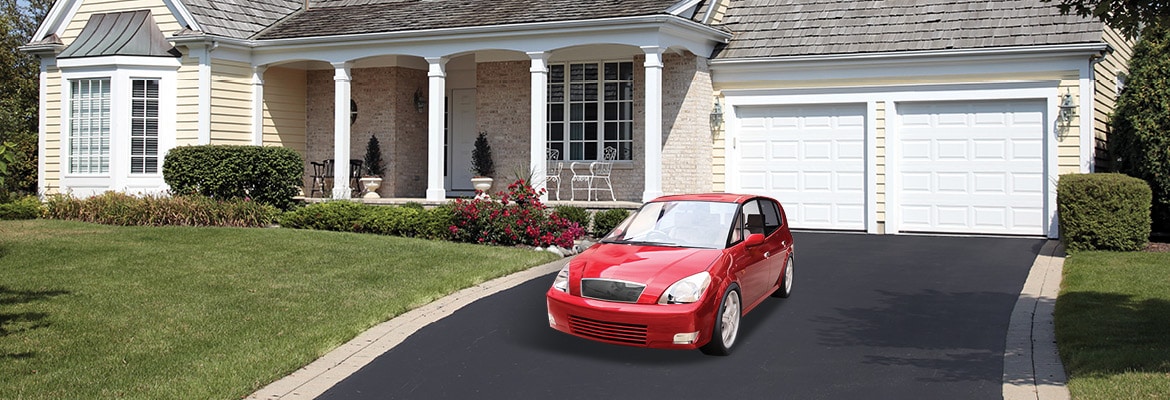 Red car delivered door-to-door in driveway of suburban home.